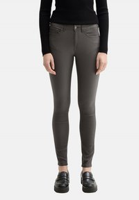 Jeans slim fit grises con una textura lisa, diseño de cinco bolsillos y detalles de costura sutiles. Combinados con mocasines negros.