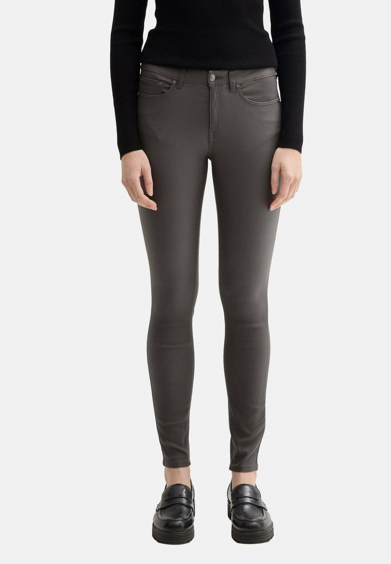 Jeans slim fit grises con una textura lisa, diseño de cinco bolsillos y detalles de costura sutiles. Combinados con mocasines negros.