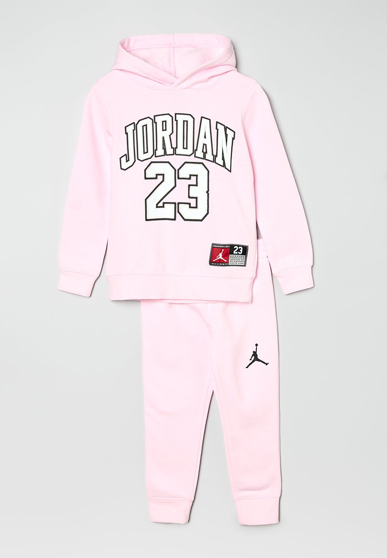 Ensemble de sweat à capuche rose et de joggings présentant "JORDAN" et "23" en noir, avec un logo Jumpman sur le pantalon. Matériau en coton, design décontracté.