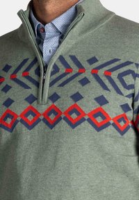 Groene pullovertrui met een kwart-rits kraag. Bevat geometrische patronen in marineblauw en rood over de borst. Gladde textuur.