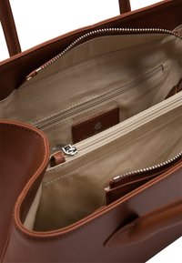 Brązowa skórzana torebka z beżowym wnętrzem, posiadająca wiele zamykanych na zamek komór oraz wszytą metkę marki w środku.