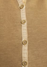 Ljusbrun knäpp cardigan med ribbad textur, sex runda knapp i neutrala färger och en slät ståndärmsknäppning framtill.