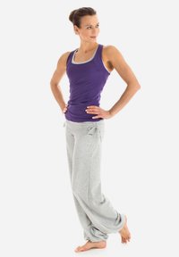 Lila Sporttanktop mit grauem Besatz, kombiniert mit lockeren grauen Jogginghosen. Der Stoff sieht weich und atmungsaktiv aus, konzipiert für Komfort.