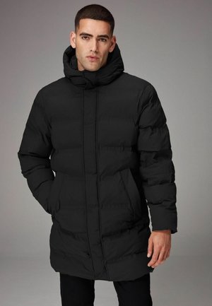 Chaqueta acolchada negra con capucha, diseño de acolchado rectangular, cierre frontal con cremallera, bolsillos laterales y una silueta de longitud media.