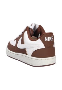 Zapatilla marrón y blanca, parte superior de cuero con acentos de malla, cuello acolchado, suela de goma y un prominente logo blanco de Nike en el talón.
