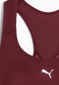 Sujetador deportivo en burdeos oscuro con un tejido texturizado y un logo blanco de Puma en la parte delantera. Tiene un diseño de espalda nadadora para brindar soporte.