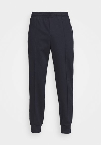 Ναυτικά βαμβακερά joggers με χαλαρή εφαρμογή, ελαστική μέση, πλάγιες τσέπες και ριμπ μανσέτες, με διακριτές κατακόρυφες ραφές.