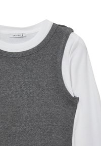 Top grigio a canotta indossato sopra una maglietta a maniche lunghe bianca. Presenta un colletto rotondo e una texture morbida a costine. L'etichetta reca la scritta "CALLIOPE."