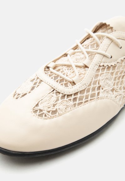 Κρέμ παπούτσι με κορδόνια μπροστά, με πάνελ από δίχτυ κεντημένα με ανθικά μοτίβα και μαύρη σόλα.