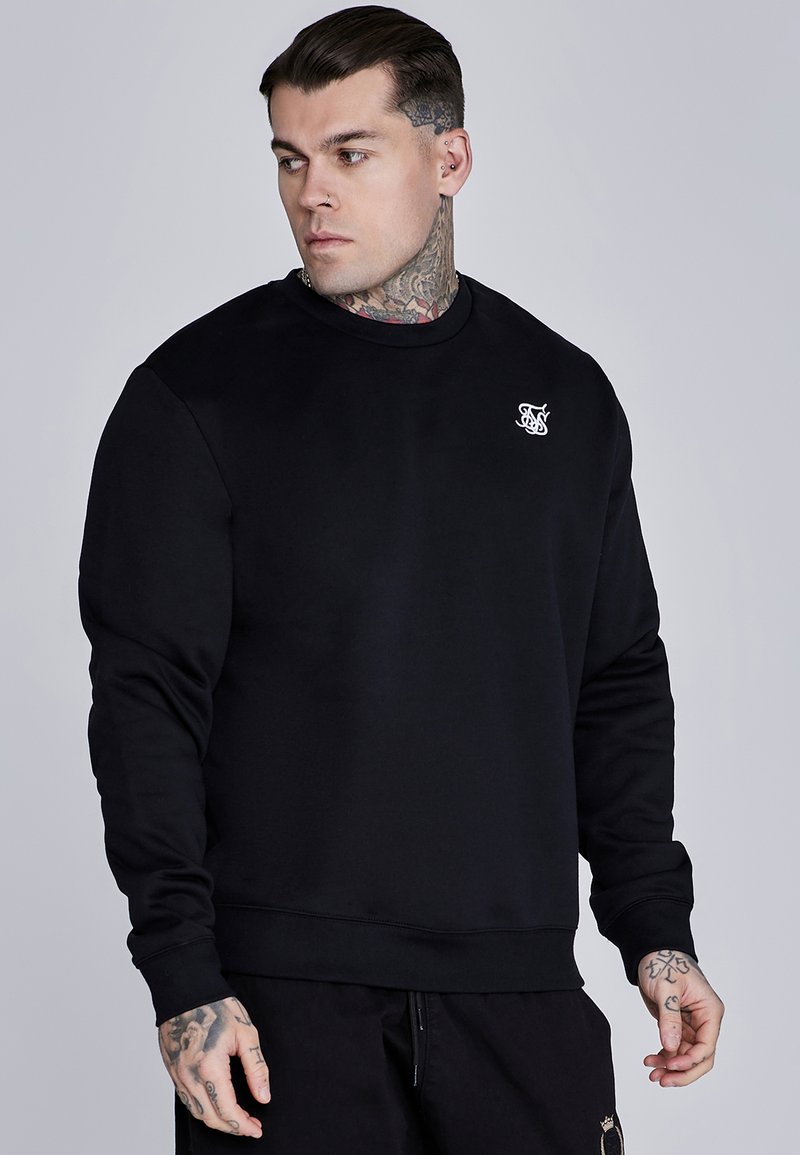 Sudadera negra hecha de una tela suave y elástica. Cuenta con un cuello redondo, mangas largas y un pequeño logo blanco en el pecho. Puños texturizados.