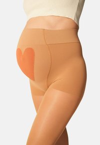 Pantaloni shorts da maternità beige realizzati in un materiale liscio ed elastico, con un design a forma di cuore arancione sul davanti, che mette in evidenza la zona della pancia.