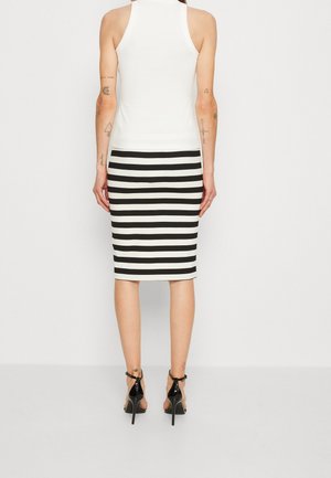 Hvid ribbet tanktop kombineret med en knælængde sort-hvid stribet blyantskirt. Sorte stiletter med stropper fuldender outfitet.