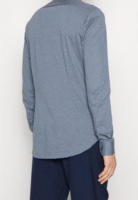 Lange mouwen shirt van lichtblauwe stof, met een puntige kraag, afgeronde zoom en knoopmanchetten. Glad textuur en ontspannen pasvorm.