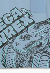 Futuristinis monstrų sunkvežimis su dideliais ratais ir tekstūruotu korpusu, lydimas stilizuoto bloko teksto riebiomis raidelėmis.