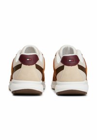 Chaussures de sport avec un mélange de maille beige, de suède marron et d'accents bordeaux. Elles disposent d'une épaisse semelle blanche et d'un détail de logo sur le talon.
