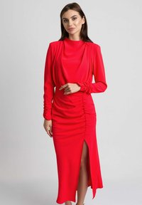 Czerwona midi sukienka z długimi rękawami, drapowany dekolt, marszczone detale i rozcięcie po boku. Gładki materiał z dopasowaną sylwetką.