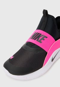 Baskets noires avec une bande élastique rose présentant le logo 'NIKE', tige en maille, semelle lisse texturée avec des éclats roses, et un Swoosh bien visible.