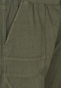 Pantalones cortos cargo de color verde oliva con una tela texturada, que presentan un bolsillo lateral y una cinturilla elástica, destacando el diseño funcional y la simplicidad.