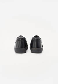 Sneaker nere in pelle con accenti in rete, dotate di suola piatta in gomma e logo sul retro. Texture liscia con design minimalista.