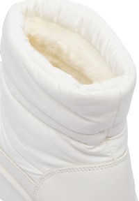 Bílé polstrované boty s měkkou krémovou podšívkou. Mají hladký vnější povrch a texturovaný horní okraj, což zajišťuje teplo a pohodlí.
