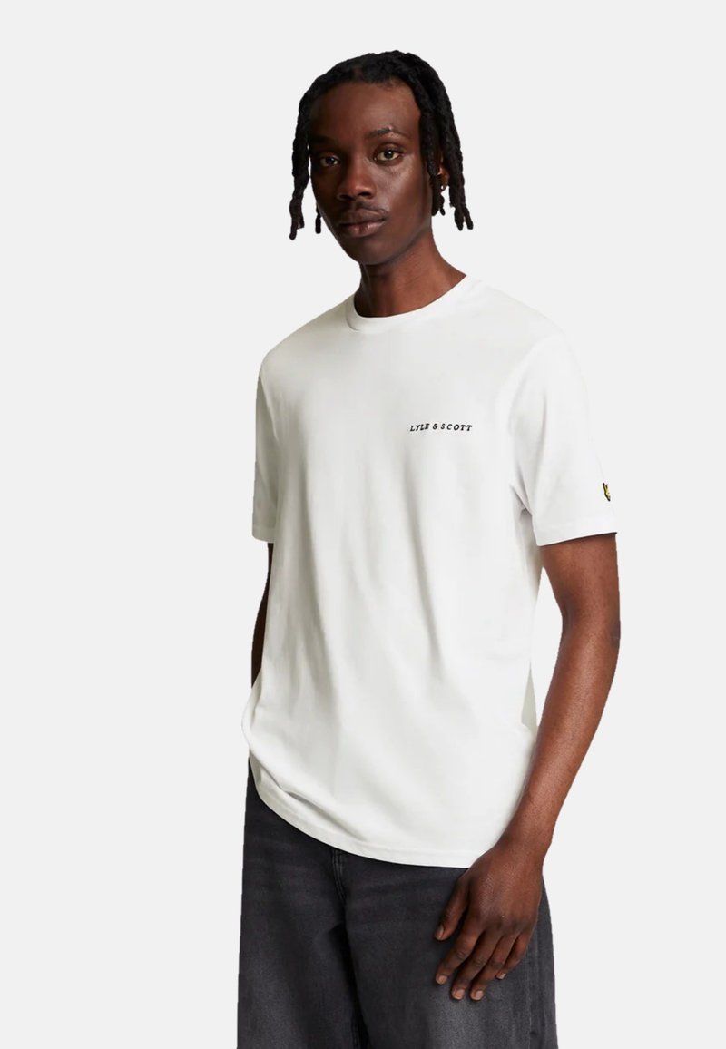 Camiseta blanca de manga corta con cuello redondo, que presenta un pequeño logo negro "LYLE & SCOTT" en el pecho y un logo amarillo en la manga.