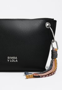 Czarna, strukturalna skórzana torba z metalowymi akcentami, ozdobiona wielokolorowym frędzlem oraz tłoczonym logo "BIMBA Y LOLA".
