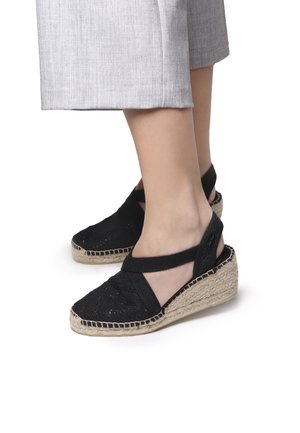 Mustat espadrilli-wedge-sandaalit, joissa on kangasjätepinta, joustavat nilkkahihnat ja juuttiköytetyllä korkkipohjalla; tekstitisoitu muotoilu ja avoin takapuoli.