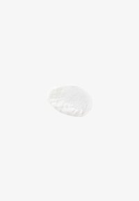 Échantillon lisse en forme ovale de crème ou lotion cosmétique blanche sur fond blanc uni avec texture visible et légères ombres.