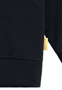 Felpa nera con orlo e polsini a costine. Include un piccolo etichetta gialla con testo. Tessuto morbido con una silhouette dal taglio classico.