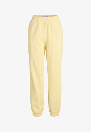 Żółte bawełniane spodnie dresowe z elastycznym paskiem w talii, bocznymi kieszeniami i ściągaczami u dołu. Gładka struktura i luźny krój.