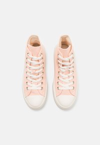 Zapatillas altas de lona rosa claro con cordones blancos, ojales de metal y una puntera de goma blanca. Textura de superficie suave.