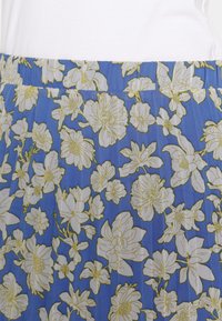Gonna maxi floreale realizzata in tessuto blu adornato con motivi di fiori bianchi e dorati, vita elastica, materiale leggero e testurizzato.
