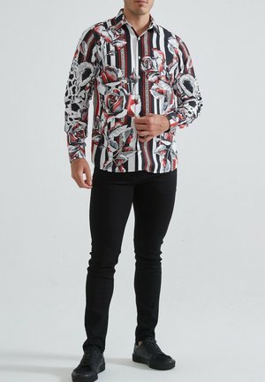 Chemise à boutons avec des rayures noir et blanc et des motifs floraux rouges. Manches longues, col, en tissu léger.