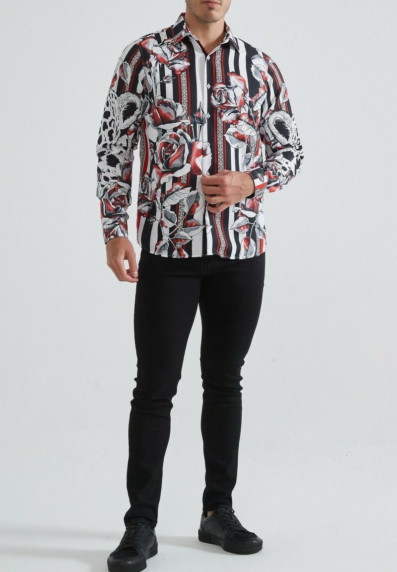 Chemise à boutons avec des rayures noir et blanc et des motifs floraux rouges. Manches longues, col, en tissu léger.