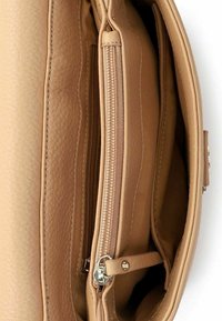 Interno di una borsa in pelle color cuoio con più scomparti e una tasca centrale con cerniera e tiretto in argento.