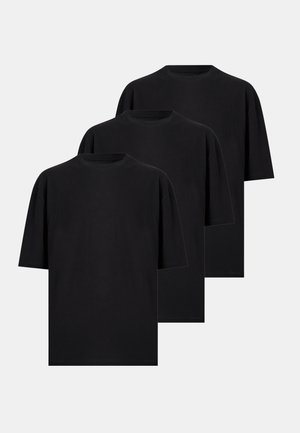 Τρία απλά μαύρα κοντομάνικα T-shirts με στρογγυλή λαιμόκοψη, που επικαλύπτονται σε ανοιχτό γκρι φόντο.