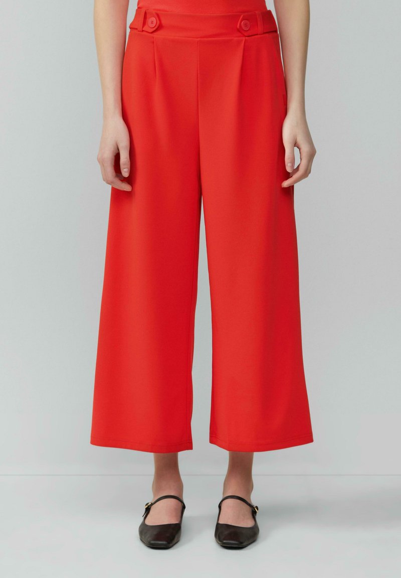 Rode wijde broek met een hoge taille, knoopaccenten op de tailleband en een zachte, gladde stof. Perfect passend voor een relaxte fit.