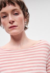 Top listrado em tecido suave, com riscas horizontais em rosa e branco, decote barco largo e mangas curtas. Textura suave.