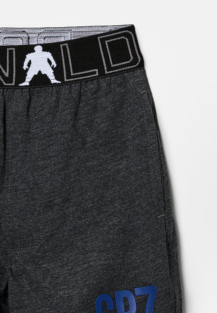 Jogging en gris foncé avec une ceinture élastique noire présentant une silhouette et des lettres blanches, et un imprimé bleu "CPZ" près de la poche.