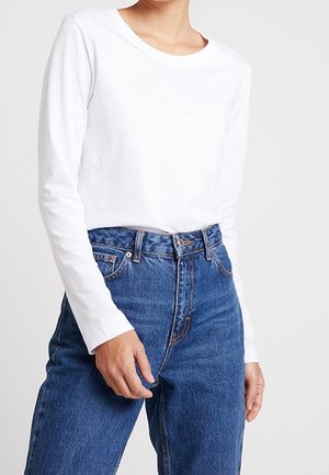 Witte langemouwshirt met een ronde halslijn, gecombineerd met hooggewaardeerde blauwe denim jeans met zichtbare stiksels en een sluiting met een knoop aan de voorkant.