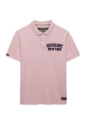 Polo à manches courtes rose clair avec col, deux boutons, et "SUPERDRY NEW YORK" brodé sur la poitrine en lettres bleu foncé.