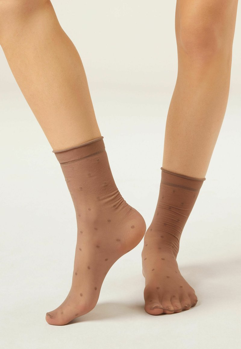 Calcetines tobilleros marrones transparentes con un patrón de puntos, puño elástico y textura suave, con un diseño ajustado que se adapta al pie.