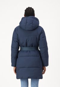 Tamsiai mėlynas pūkinis paltas su kapišonu, diržu juosmenyje, su Calvin Klein ženklu ir s quiltingo dizainu, vidutinio ilgio.