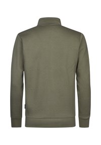 Jersey verde oliva con un patrón de zigzag texturizado, cuello alto y puños acanalados. Diseño sencillo sin logotipos ni adornos visibles.