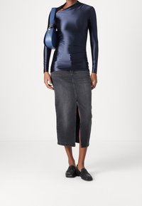 Mørkeblå satin langærmet top parret med en mørkegrå denim midi-nederdel med en frontslids. Matchende med sorte slip-on sko og en blå taske.