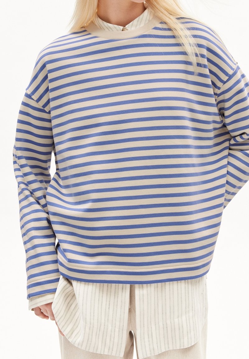 Bluzka w paski z długim rękawem w kolorze kremowo-niebieskim. Miękki, elastyczny materiał o luźnym kroju. Okrągły dekolt i opuszczone ramiona.