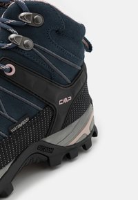Botte de randonnée imperméable bleu foncé avec une semelle noire antidérapante, des œillets en métal et le logo CMP sur le côté et le talon.
