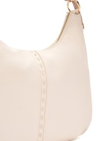 Borsa a tracolla in pelle beige con una texture liscia, forma arcuata, una cerniera laterale e cuciture decorative lungo la cucitura. Accenti hardware rotondi.