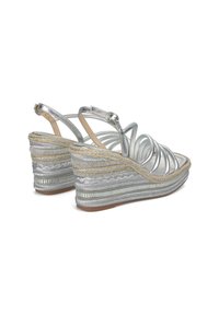 Sandali wedge argento con cinturini incrociati, dotati di una suola in juta tessuta texturizzata e dettagli metallici. Design superiore trasparente.