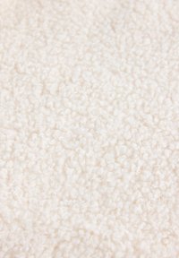 Tessuto bianco con una superficie morbida e pelosa. Il materiale presenta piccole anse fitte che creano un aspetto soffice.